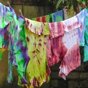Mehrere bunte Batik-Shirts hängen nebeneinander an einer Wäscheleine im Freien