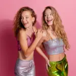 Zwei Frauen in funkelnder Glitzerkleidung vor rosa Hintergrund