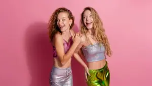 Zwei Frauen in funkelnder Glitzerkleidung vor rosa Hintergrund